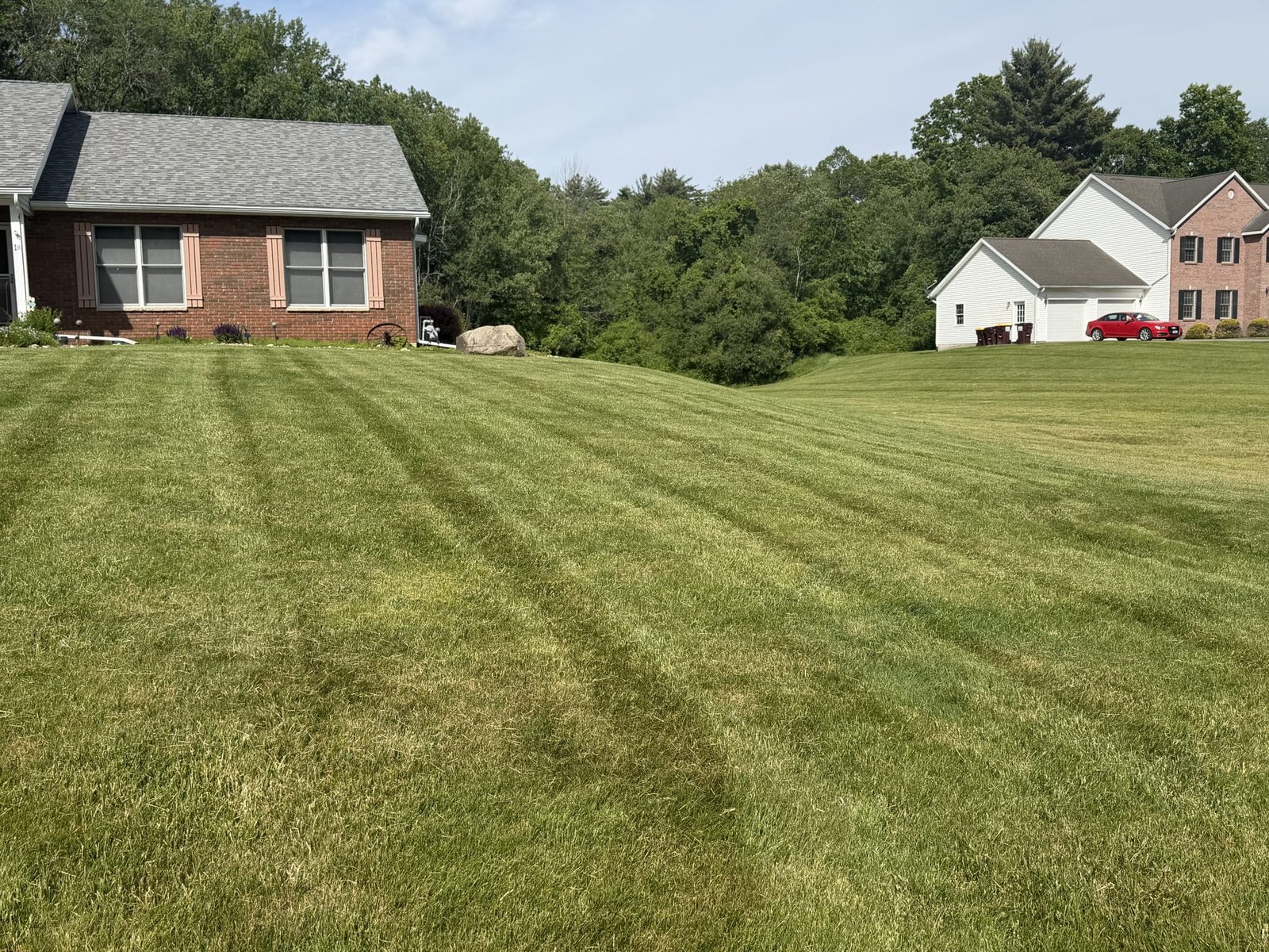 A striped, freshly mowed lawn running between two neighboring homes.