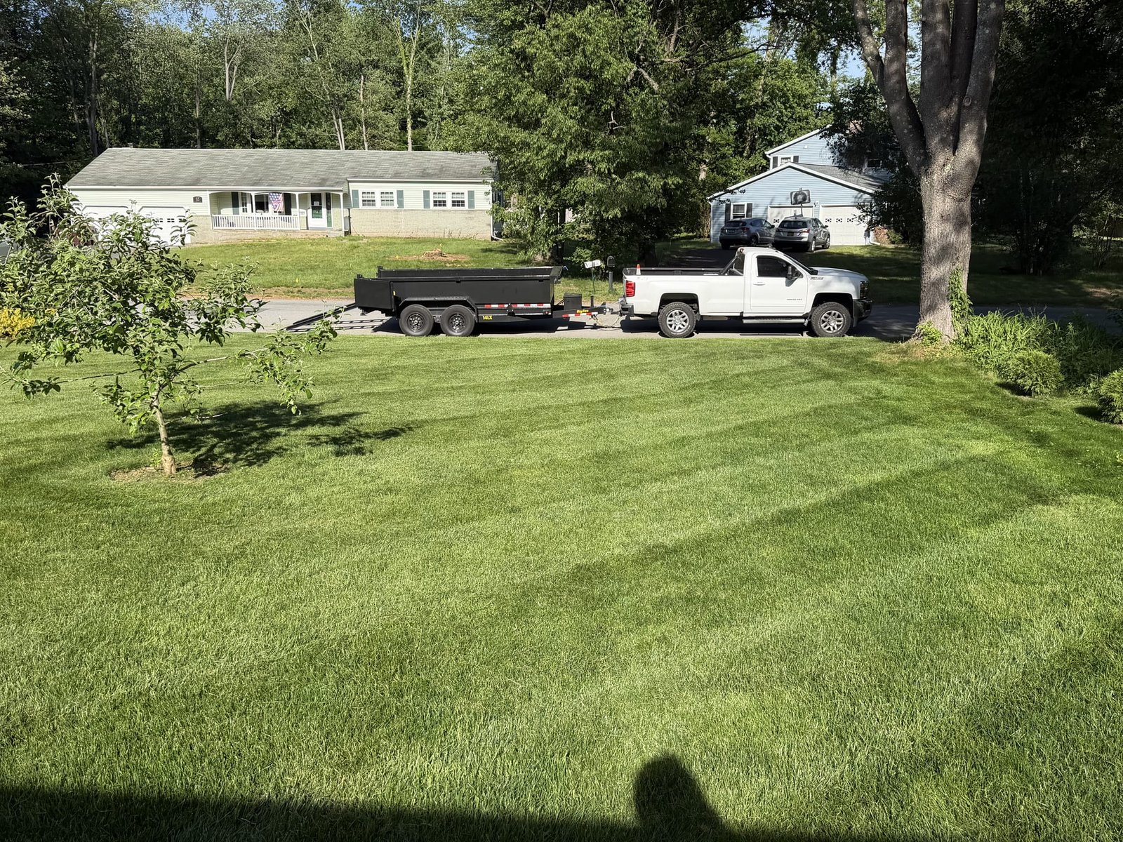 A freshly striped front yard with the work truck and trailer parked at the curb.