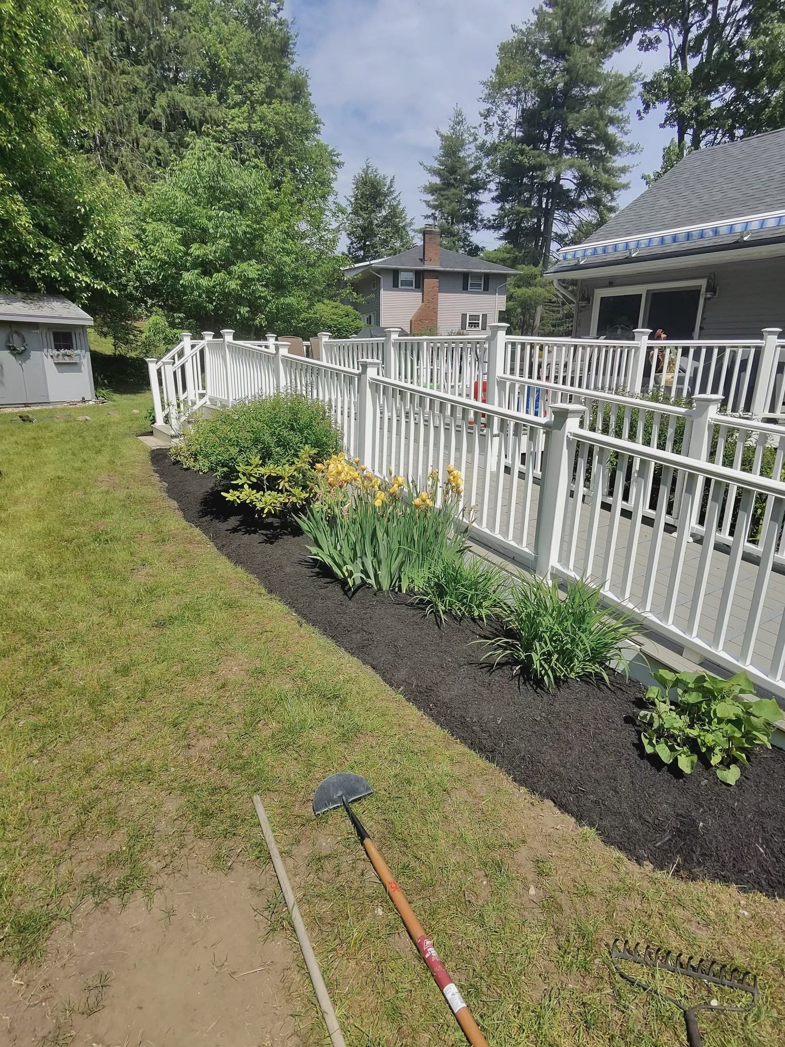 A freshly planted bed of daylilies running along a white deck.