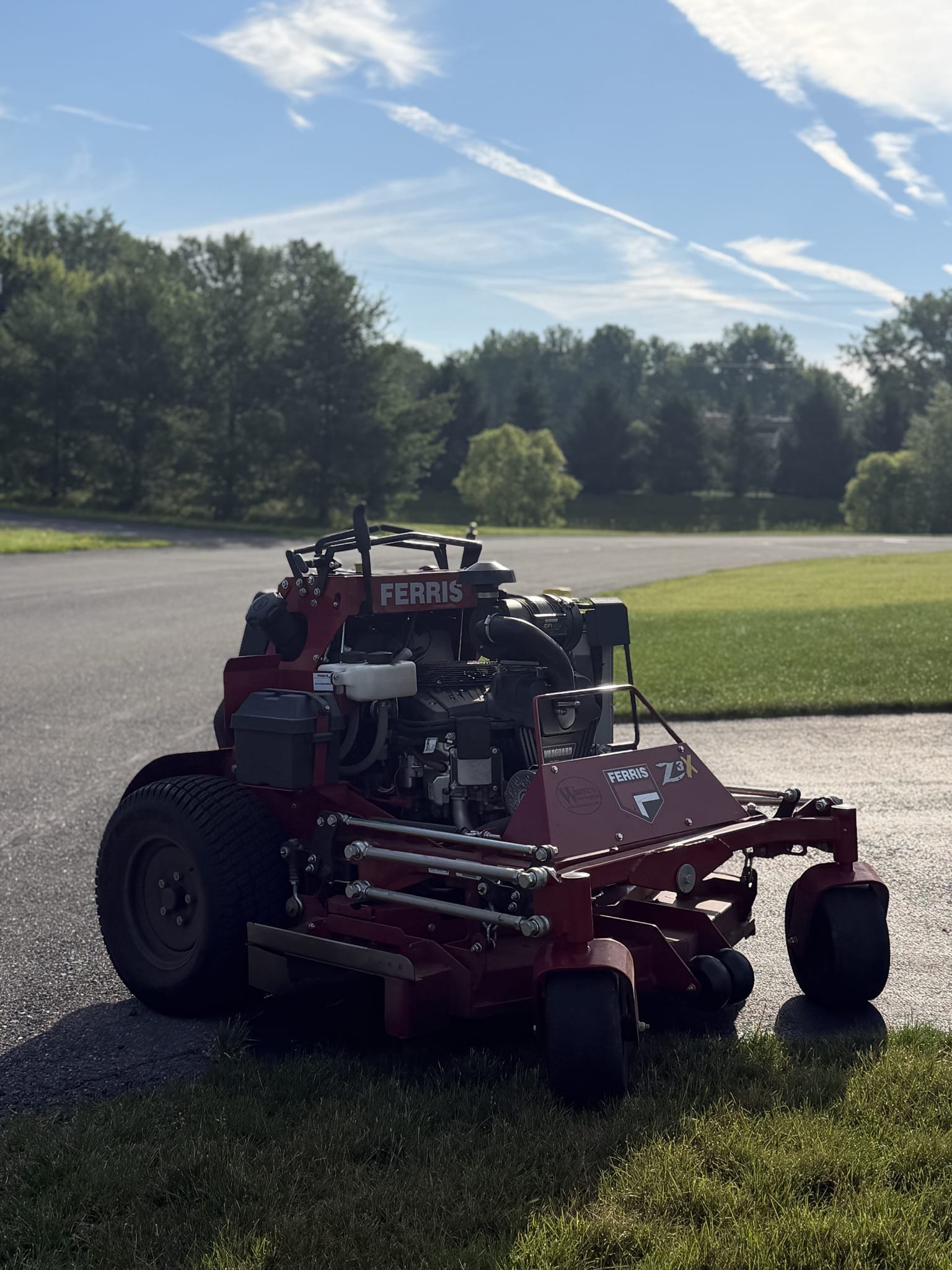 Ferris stand-on mower staged at the edge of a lawn in early morning light