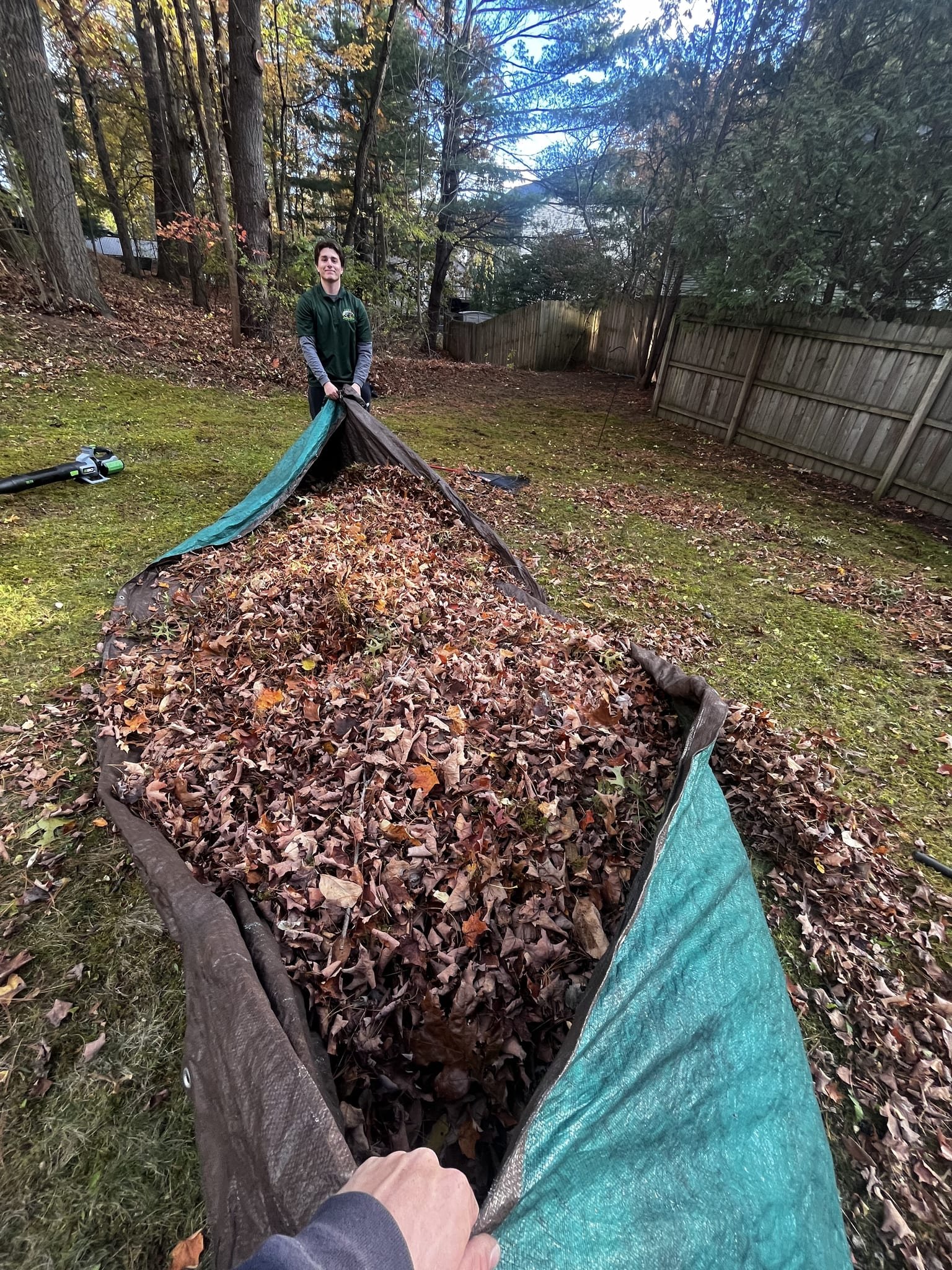 Crew member dragging a loaded leaf tarp during a fall cleanup