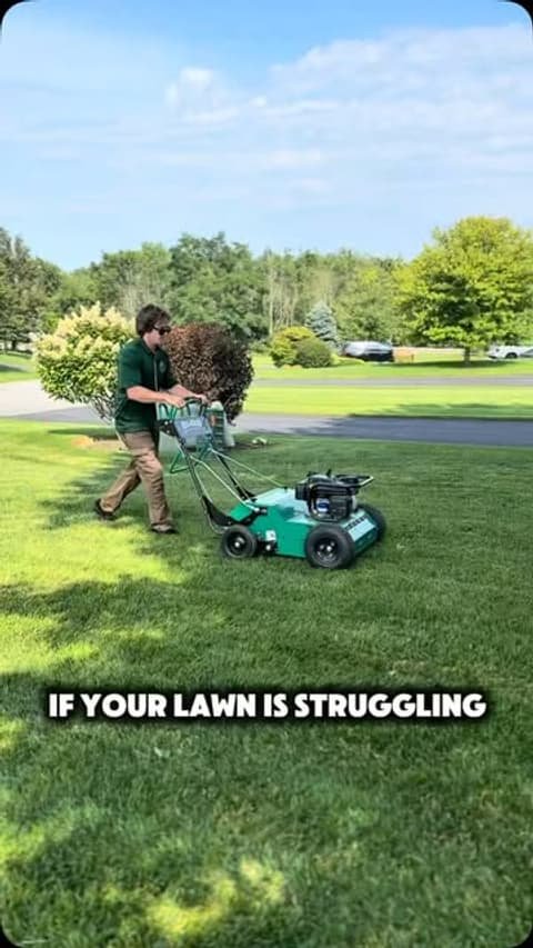 Crew running a core aerator across a green lawn