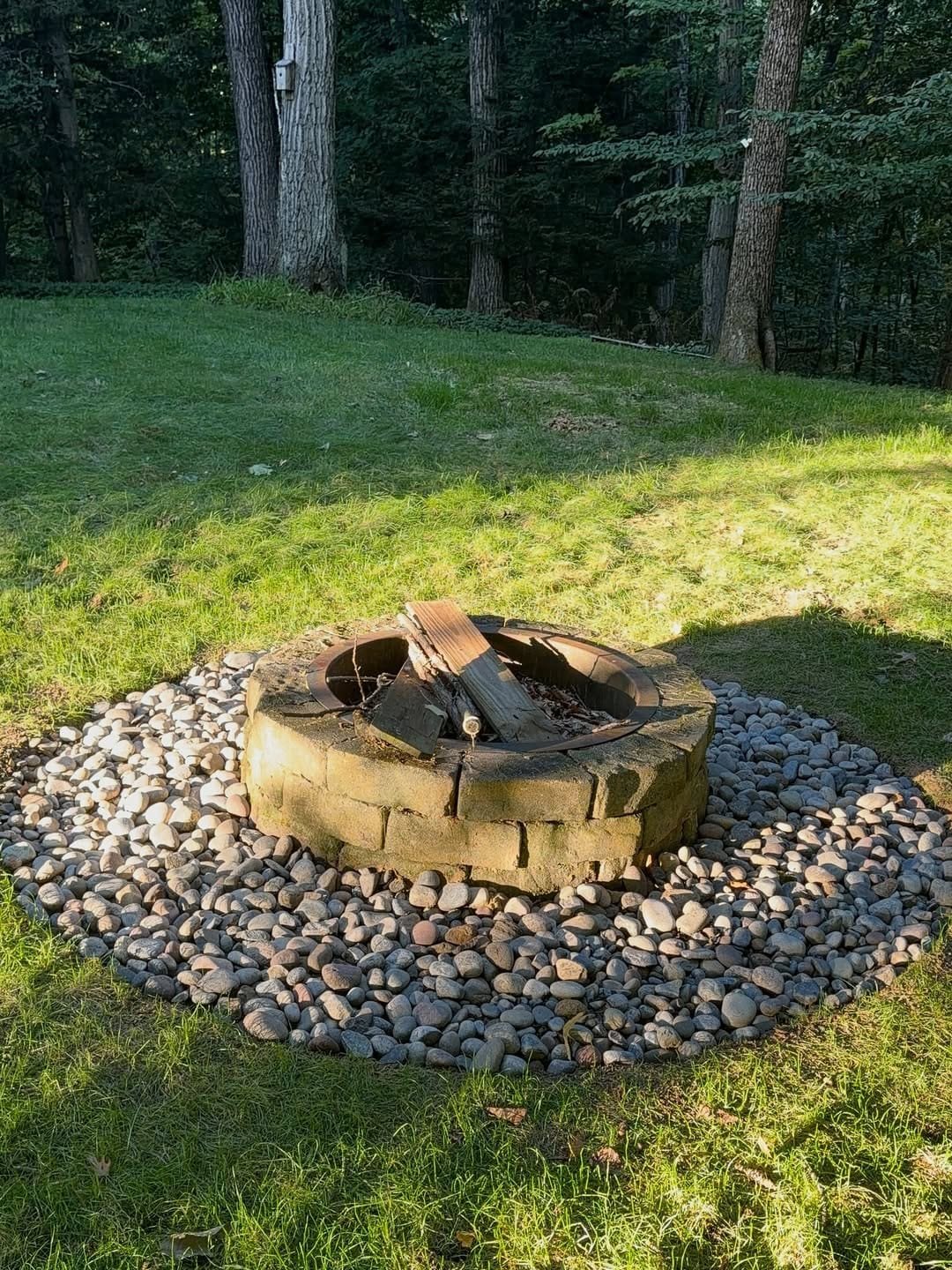 Same stone fire pit ringed with a wide bed of river rock