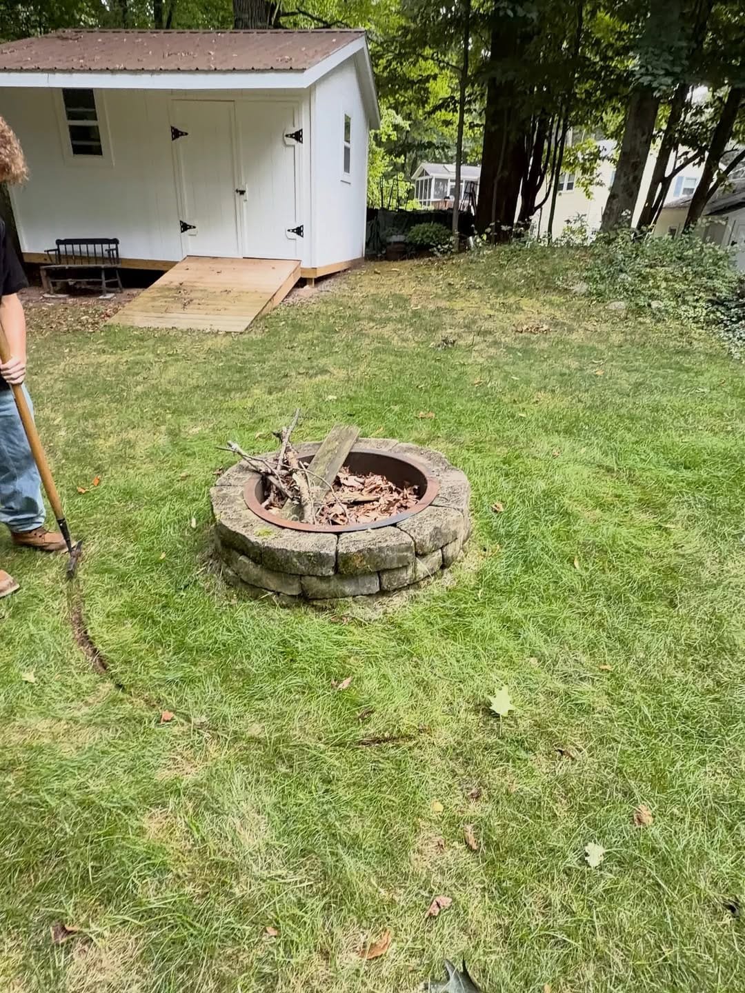 Stone fire pit sitting in patchy grass before the river rock ring went in